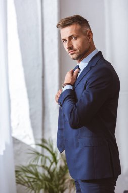 yakışıklı adam kravat takıyor ve kameraya bakarak elbiseli