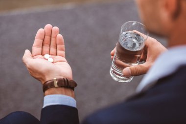 işadamı su ve hapları tutan takım elbiseli kırpılmış atış  