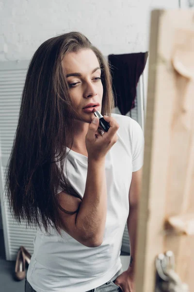 Joven Mujer Transgénero Aplicando Lápiz Labial Mientras Mira Espejo Casa — Foto de Stock