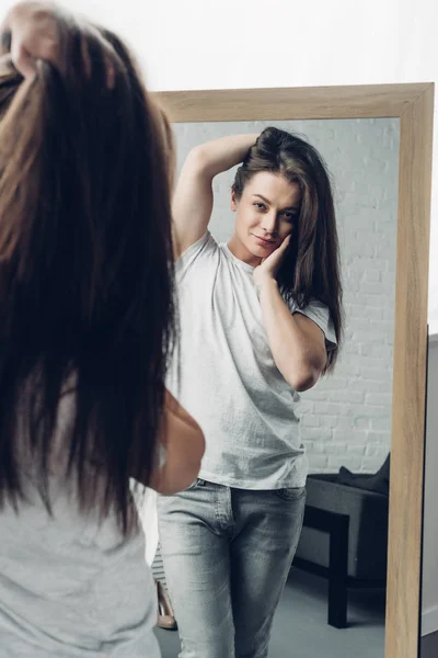 年轻变性妇女穿着白色T恤 看着家里的镜子 — 图库照片