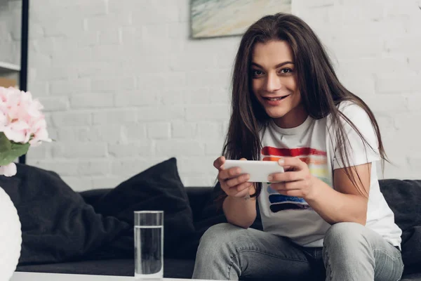 Lächelnde Junge Transgender Frau Mit Smartphone Auf Der Heimischen Couch — Stockfoto