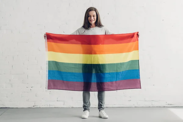 Joven Mujer Transgénero Sosteniendo Bandera Orgullo Frente Pared Ladrillo Blanco —  Fotos de Stock