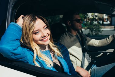 smiling woman looking out car window while boyfriend driving car clipart