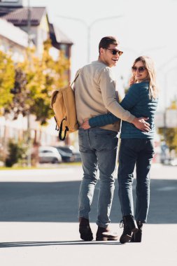 arkadan sarılma ve yeni şehir sokakta yürürken kameraya bakarak bir çift görünüşü