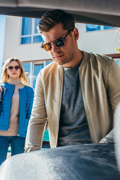 Hombre Poniendo Equipaje Coche Mientras Novia Pie Detrás Calle — Foto de stock gratis