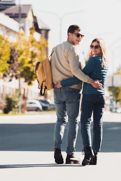 arkadan sarılma ve yeni şehir sokakta yürürken kameraya bakarak bir çift görünüşü