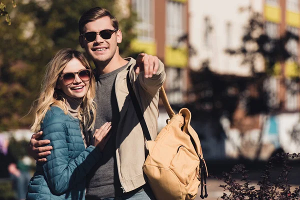 portrait of man showing something to girlfriend while walking together in new city