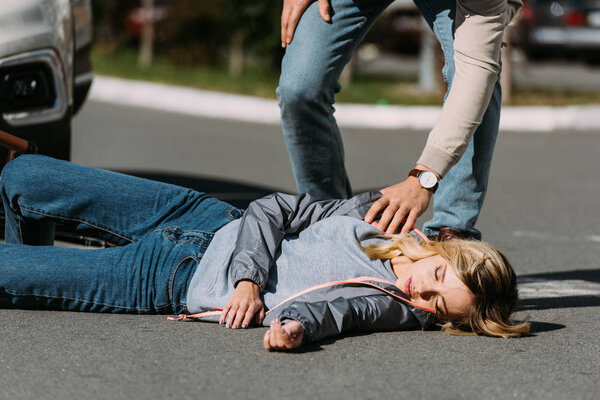 partial view of young woman mowed down by driver in car on road, car accident concept