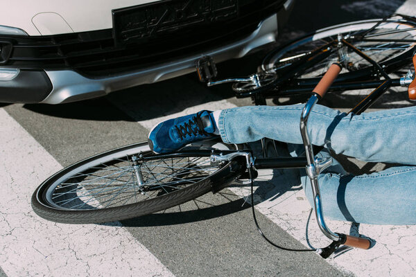 partial view of male bicycle rider hit by car on road, car accident concept