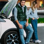 Upset young couple near broken car on street