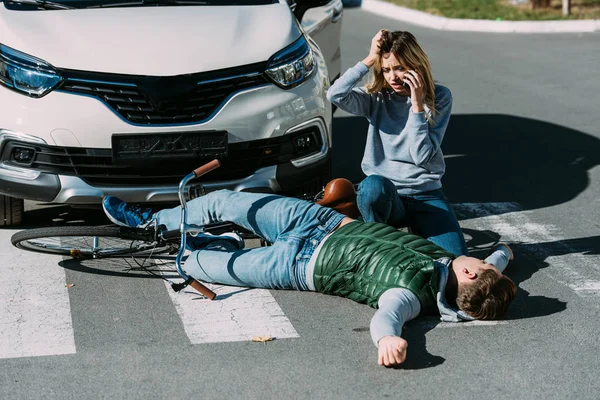 Jovem Mulher Chamando Emergência Olhando Para Ciclista Ferido Deitado Estrada — Fotografia de Stock