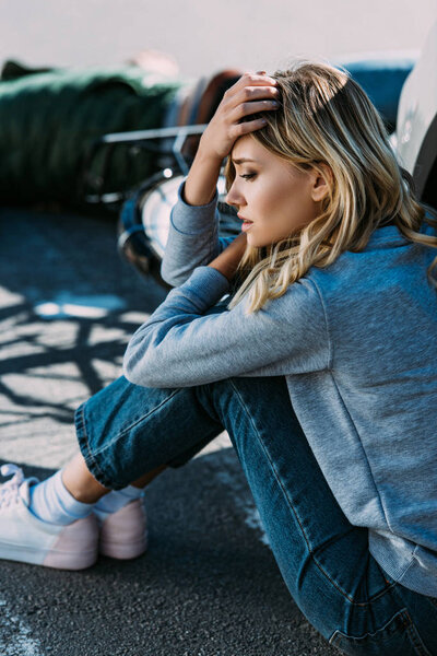 молодая женщина плачет возле автомобиля после аварии с велосипедистом
 