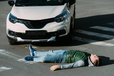 high angle view of injured young man lying on road after motor vehicle collision clipart