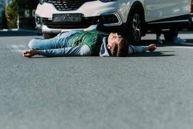 surface level of injured young man lying on road after car accident clipart