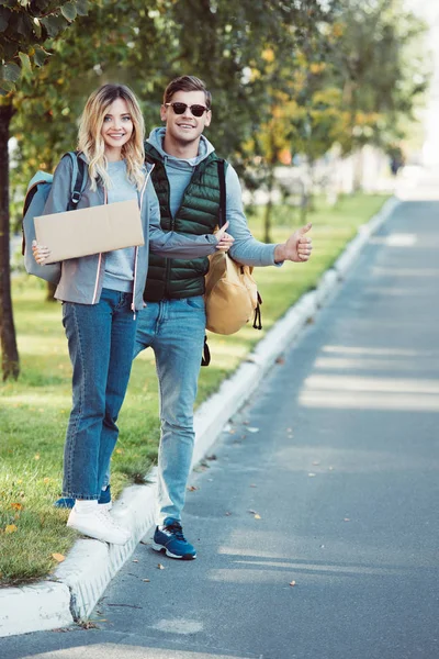 Feliz Joven Pareja Autoestopistas Sosteniendo Tarjeta Blanco Sonriendo Cámara — Foto de stock gratuita