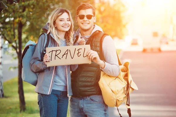 Feliz Jovem Casal Viajantes Segurando Cartão Com Viagem Inscrição Sorrindo — Fotografia de Stock