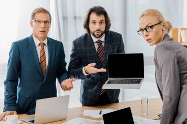 işçiler ile ayakta ve office içinde laptop gösteren genç ciddi erkek sigorta acentesi