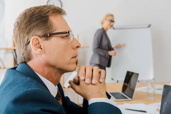 Thoughtful Adult Man Sitting Table Young Woman Pointing White Board — Stock Photo, Image