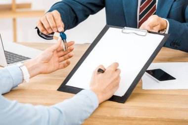 insurance agent giving keys and contract for signing on clipboard to woman  clipart