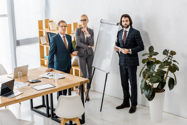 office workers standing near white board and having discussion 