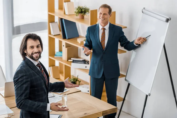 insurance workers having discussion at meeting and smiling man pointing at white board in office