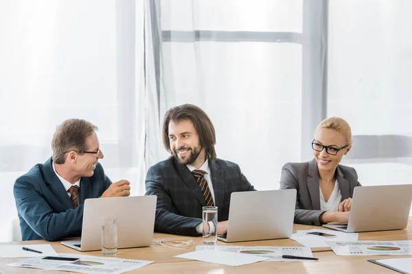 Trabajadores Seguros Sentados Mesa Con Computadoras Portátiles Hablando Oficina — Foto de stock gratis