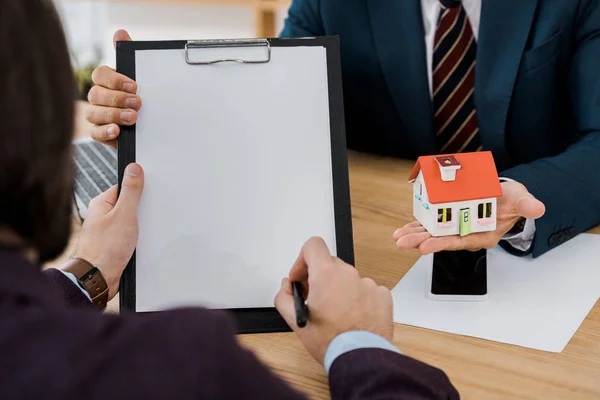 Man Signing Contract Clipboard While Insurance Agent Holding House Model — Stock Photo, Image