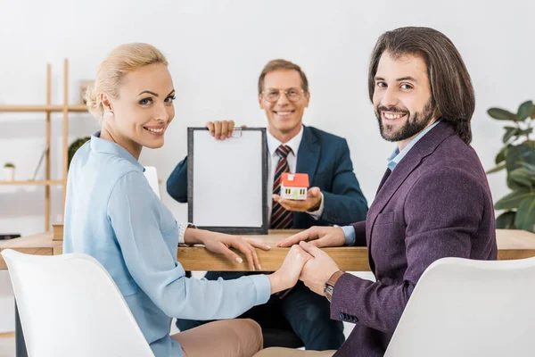 Feliz Pareja Tomados Mano Mientras Que Agente Seguros Muestra Contrato — Foto de Stock