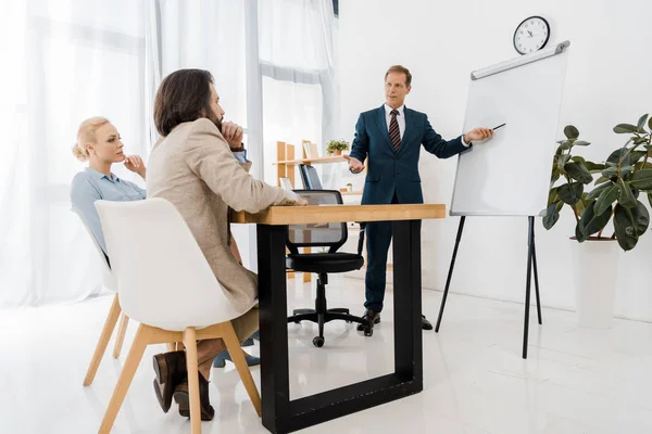 Affärsman Som Pekar Whiteboard Medan Paret Sitter Office — Stockfoto