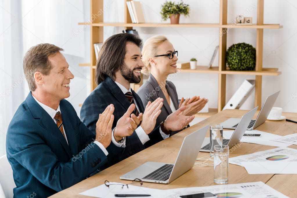 happy business people clapping hands at meeting in office