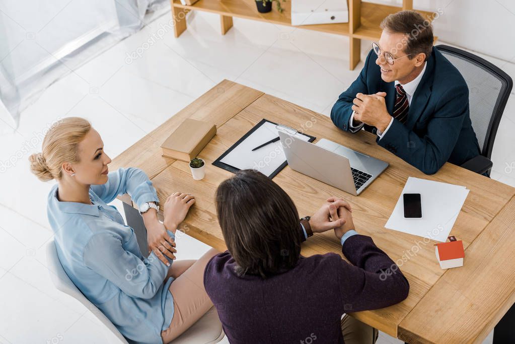 adult insurance agent in glasses talking to young couple in office