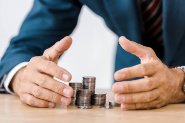 businessman grabbing silver coins at wooden table