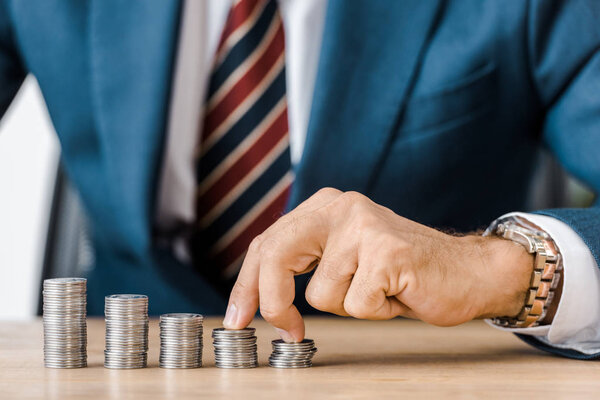 male hand counting silver coins at wooden table