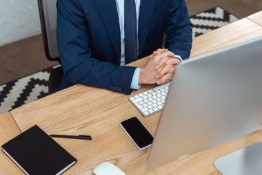 yakışıklı işadamı bilgisayar ve modern ofisindeki smartphone ile masada oturan resim kırpılmış