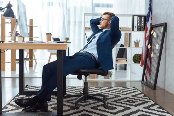 Konzentrierter Geschäftsmann Mit Brille Sitzt Mit Den Händen Hinter Dem — kostenloses Stockfoto