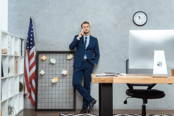 Guapo Hombre Negocios Traje Hablando Teléfono Inteligente Cerca Bandera Americana —  Fotos de Stock