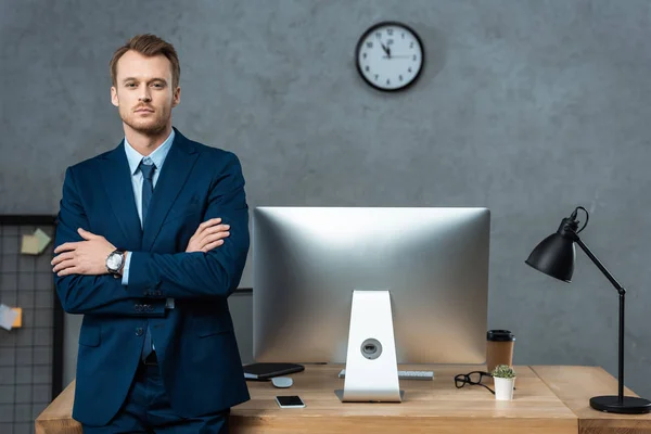 Stilig Affärsman Står Med Korsade Armar Nära Bord Med Datorskärm — Stockfoto