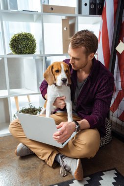Dizüstü holding beagle yakınındaki ev ofis ABD bayrağı ile erkek serbest meslek 