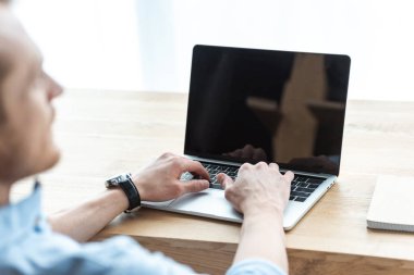 ofiste tabloda boş ekran ile dizüstü bilgisayar üzerinde çalışan işadamı kısmi görünümü 