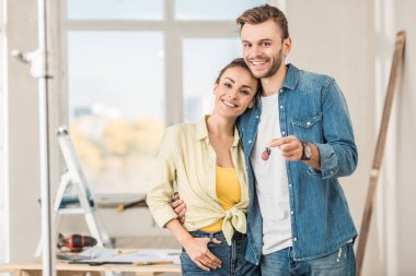 happy young couple holding key from new apartment and smiling at camera clipart