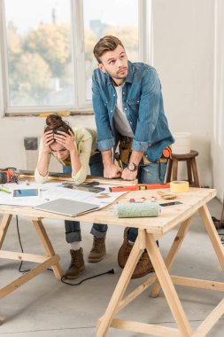 upset young couple leaning at table with tools during repairment clipart