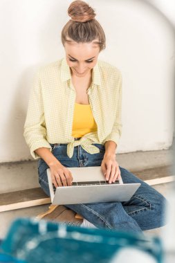 high angle view of smiling young woman using laptop while sitting at new home clipart