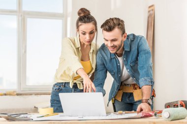 young couple using laptop during home improvement clipart