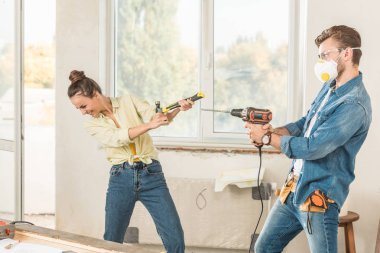 happy young couple having fun with tools during repairment in new apartment clipart