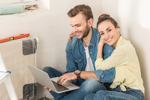 Sonriente Joven Pareja Usando Ordenador Portátil Mientras Está Sentado Piso — Foto de stock gratis