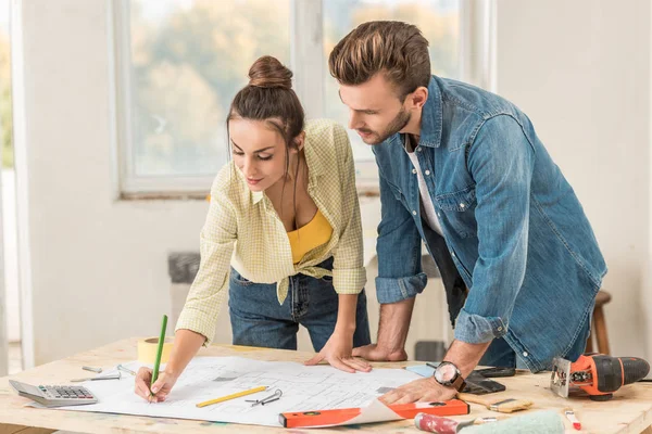 Young Couple Marking Blueprint Discussing Renovation Together — Stock Photo, Image