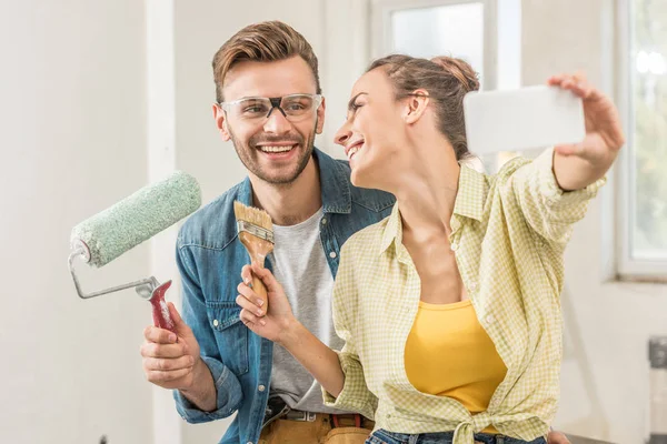 Feliz Joven Pareja Sosteniendo Herramientas Tomando Selfie Con Teléfono Inteligente — Foto de Stock