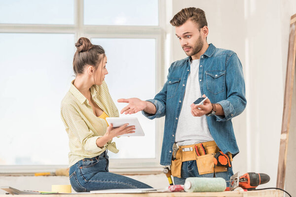 shocked young couple using digital devices during repairment