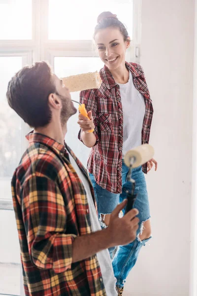 Feliz Pareja Joven Sosteniendo Rodillos Pintura Divertirse Mientras Hacen Reparación —  Fotos de Stock