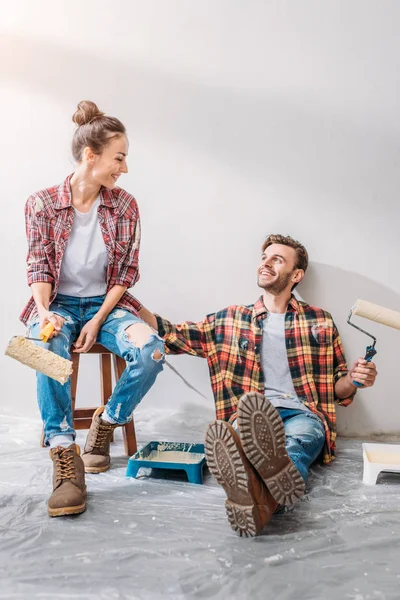 Kareli gömlek tutan genç çift silindirler ve birbirlerine gülen boya